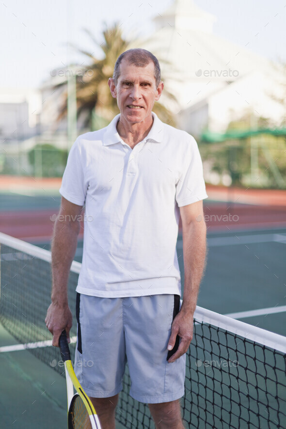 Older man with tennis racket on court Stock Photo by ImageSource