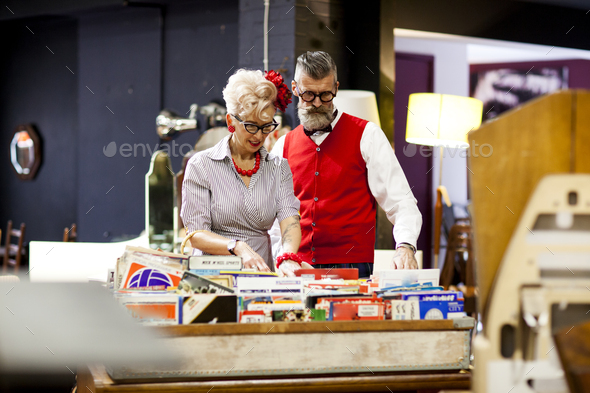 Quirky vintage couple looking at vinyl records in antique and vintage emporium