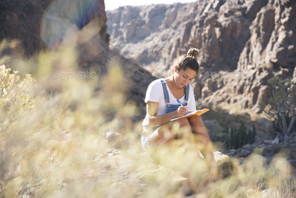Young female hiker writing notes in valley, Las Palmas, Canary Islands, Spain