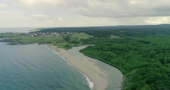Aerial view of sea and coastline  and city among green area of  forest alt