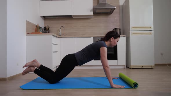 A Young Sportswoman in Black Leggings and a Gray Tshirt Performs Pushups