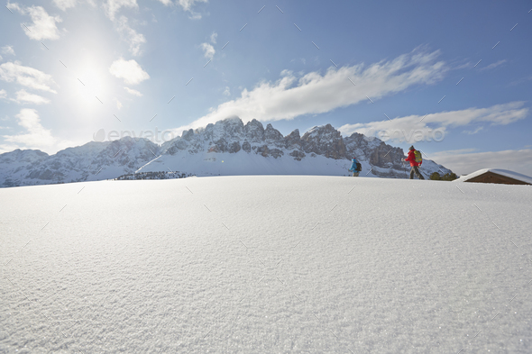 Distant view of mid adult couple snowshoeing, Dolomites, Eisack Valley, South Tyrol, Italy