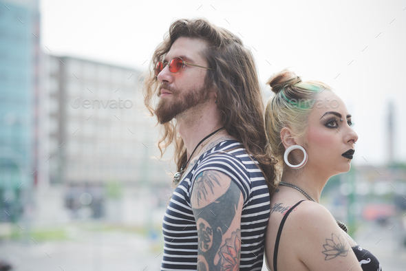 Portrait of punk hippy couple back to back on city street
