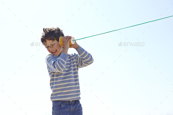 Young boy, holding cup and string telephone to ear