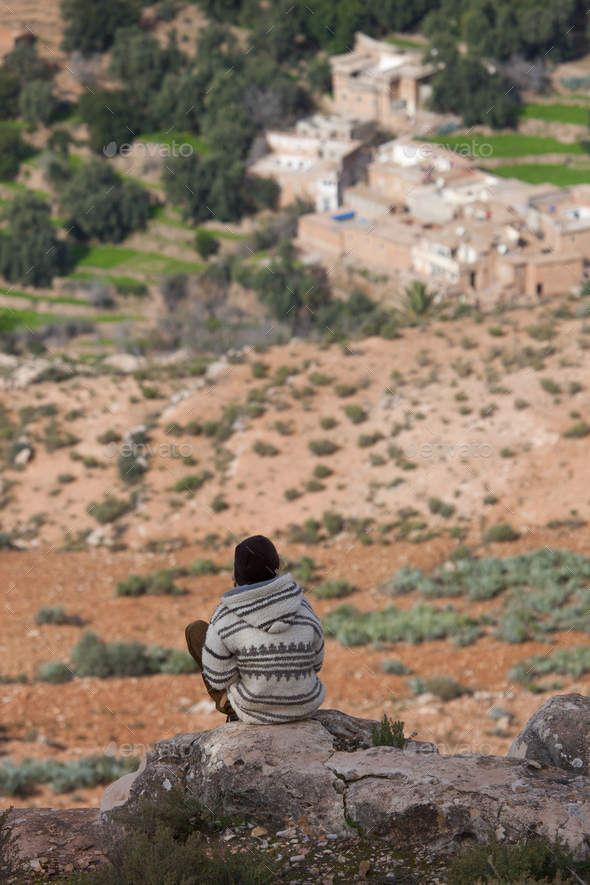 Rear view of man sitting on rocks above valley, Atlas Mountains, Morocco