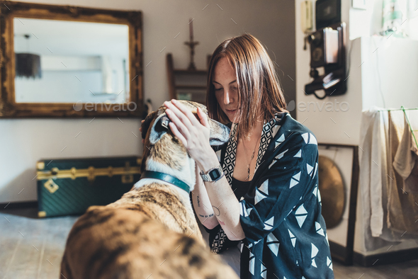 Young woman petting her dog in apartment