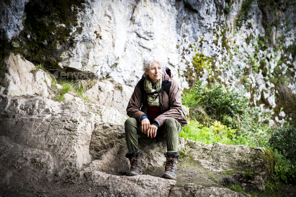 Woman hiker sitting on rocks looking away, Bruniquel, France