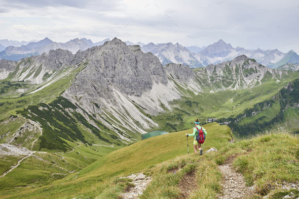 Rear view of female hiker hiking down valley in Tannheim mountains, Tyrol, Austria