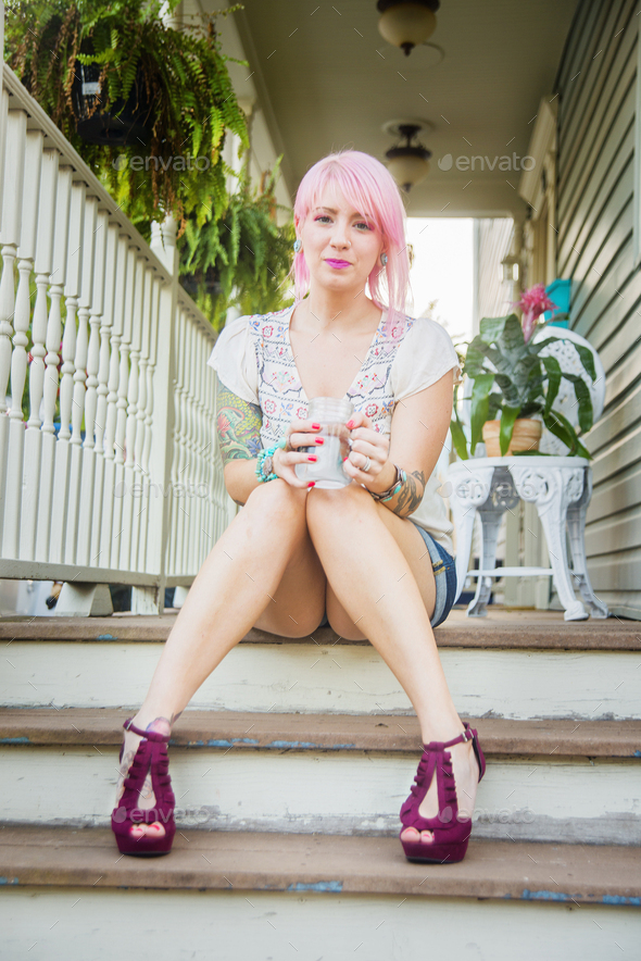 Portrait of young woman with pink hair sitting on porch steps