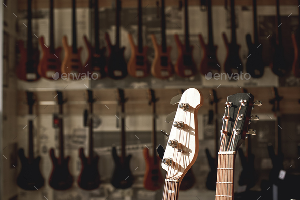 Close-up view of two guitar headstocks againt of a row of different electric guitars aligned in a