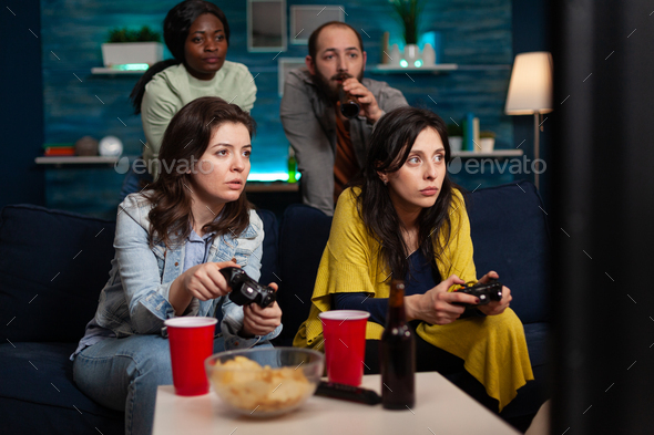 Concentrated women relaxing on couch playing video games using controller