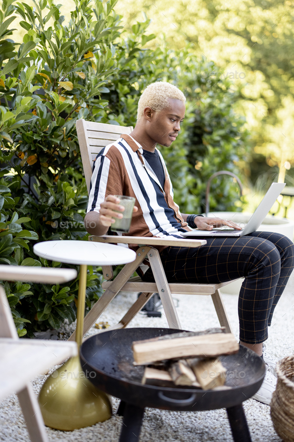 Latin man using laptop on lounger at house garden