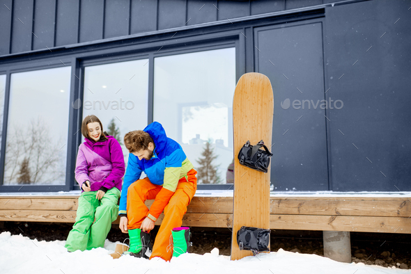 Couple in ski suits near the modern house in the mountains