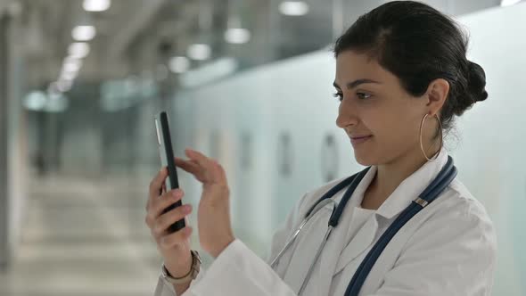 Relaxed Indian Female Doctor Using Smartphone in Cafe alt