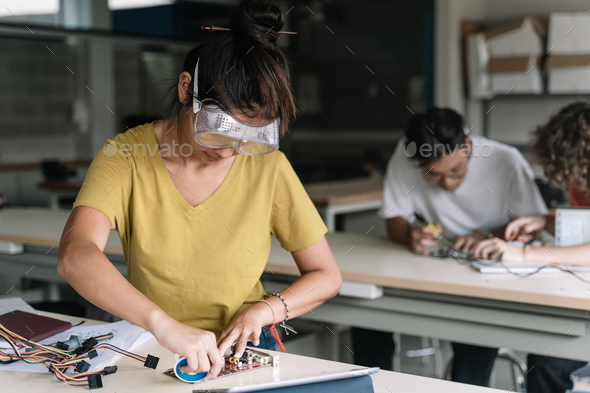 Asian High School teenager Student wearing protective goggles working on electronics circuit board