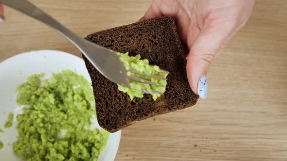 A Woman's Hand Takes a Sandwich From an Avocado and Guacamole Sandwich alt