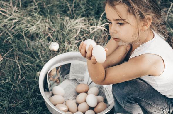 Little girl holding and picking good eggs quality organic and bring to the eye on the farm.