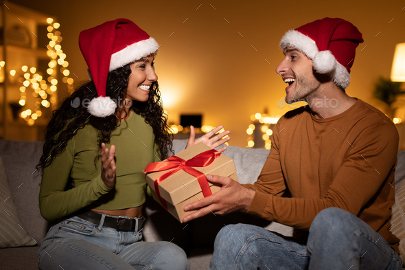 Husband Giving Christmas Gift To Wife Congratulating Her At Home