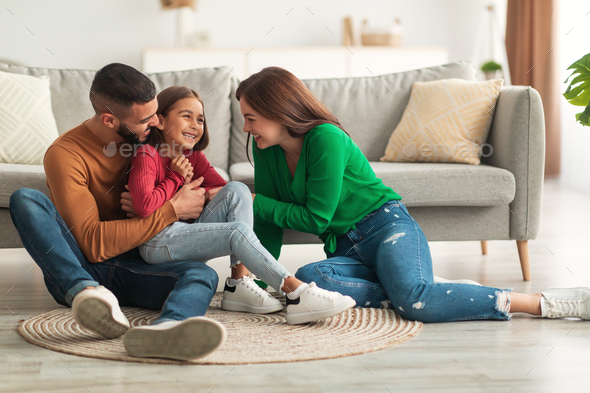Portrait of a happy Arab family tickling daughter at home