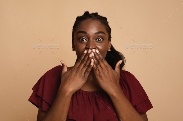 Excited black lady looking at camera, covering her mouth