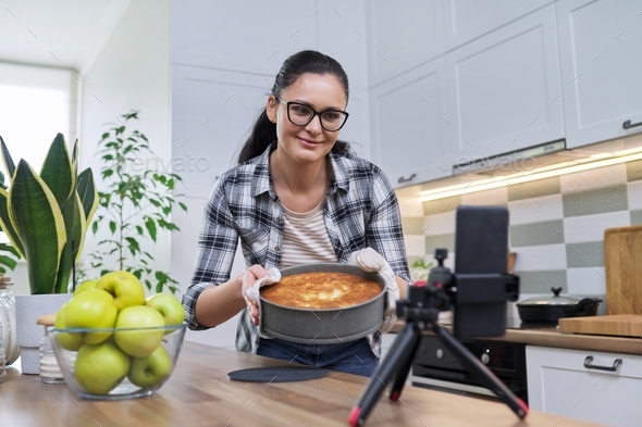 Female recording video of an apple pie recipe on smartphone at home in the kitchen