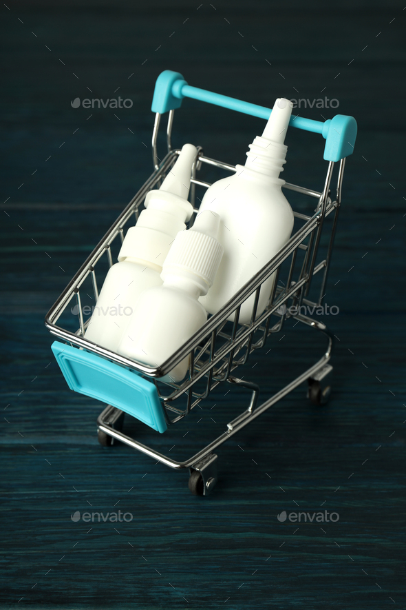 Shop trolley with bottles of nasal spray on wooden background
