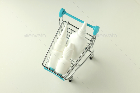 Shop trolley with bottles of nasal spray on white background