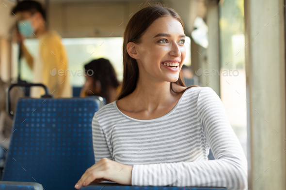Smiling excited lady taking bus, looking at window