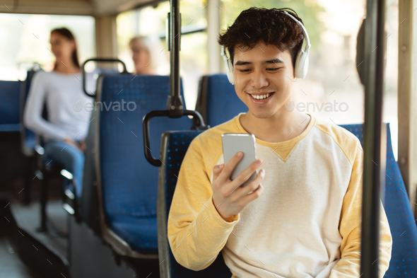 Happy smiling asian man listening music in bus