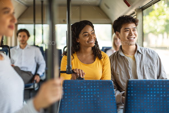 Happy asian guy and black lady taking bus together