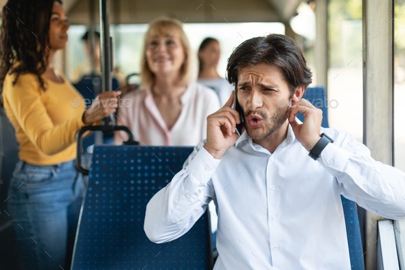 Confused guy talking on phone holding finger in ear