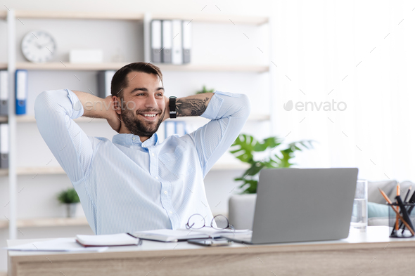 Cheerful adult european guy have break from work at laptop with hands behind his head