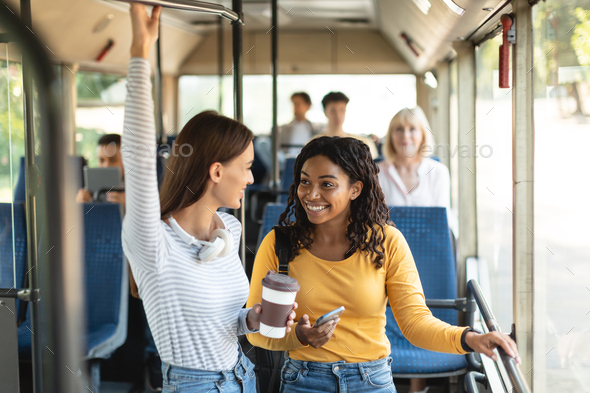 Beautiful smiling ladies standing in bus and talking Stock Photo by ...