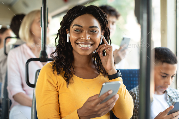 Happy black woman listening music in bus Stock Photo by Prostock