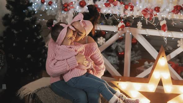 Happy Mother Having Fun with Her Daughter Near Christmas Tree in Pink Pullovers alt