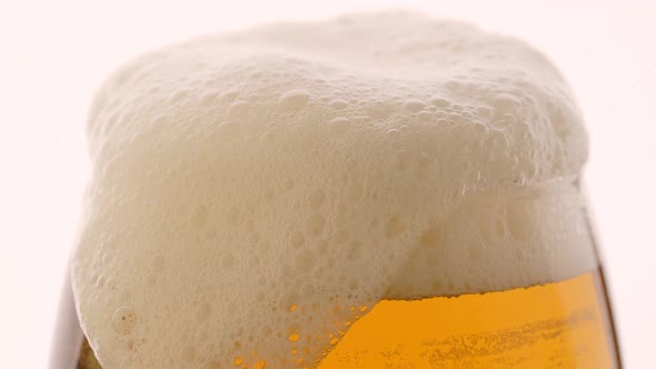 Glass of Beer with Froth in Slow Motion on White Background