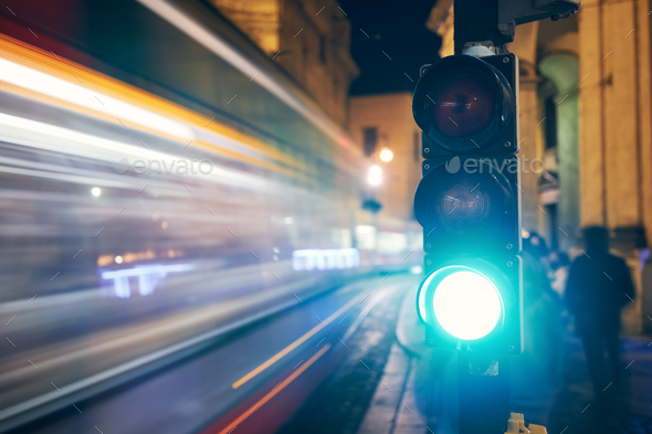 Green on traffic light against light trails of tram - Stock Photo - Images