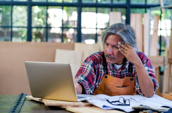 Senior Asian craftsman act as feel bad or sad with something appear on laptop screen
