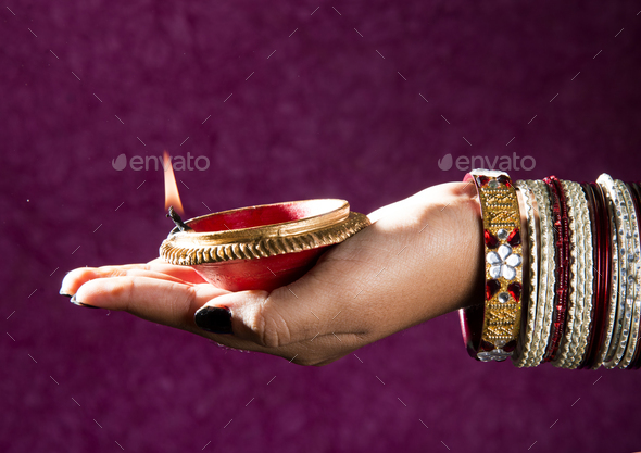 Female hand holding lit earthen lamp at Diwali festival in India - Stock Photo - Images