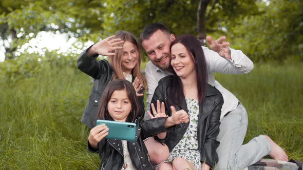 Positive Family Sitting Together on Soft Plaid Utdoors and Taking Selfie on alt