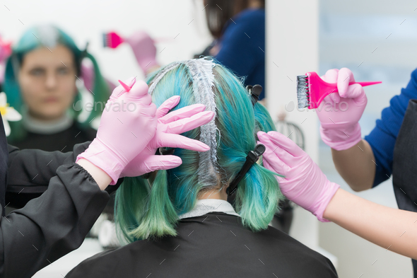 Process of hair dyeing in beauty salon. Hairdressers apply paint to hair during bleaching hair roots