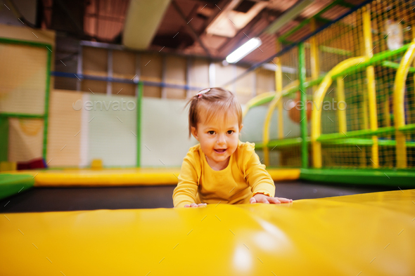 Cute baby girl jumping on a trampoline in indoor play center.