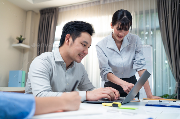 Asian attractive businessman work on computer follow direction from businesswoman leader in office.