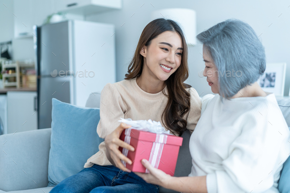 Mother's Day gift. Happy asian girl greeting young surprised mom, giving  her handmade card and wrapped gift box Stock Photo - Alamy