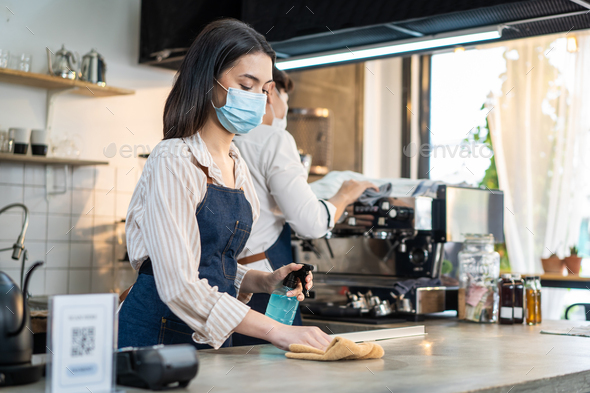 Cafe waiter wear mask, clean restaurant with sanitizer to open store.