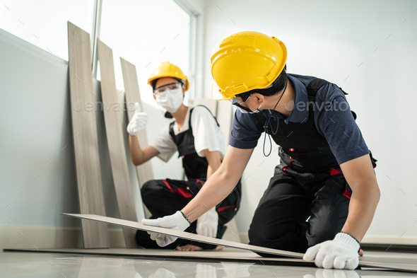 Asian builder worker people wear mask installs laminate board on floor.