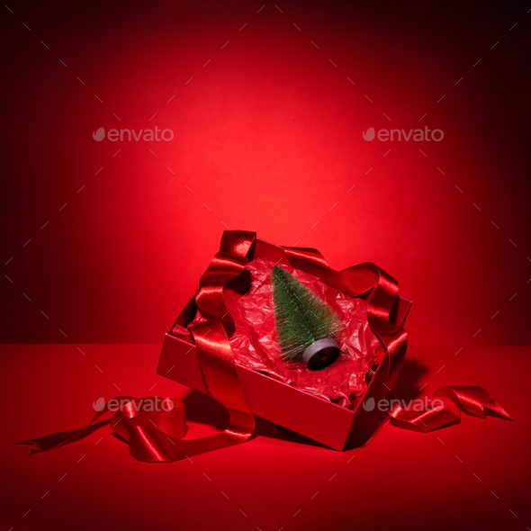 Red gift box with ribbon and Christmas tree. Conceptual composition