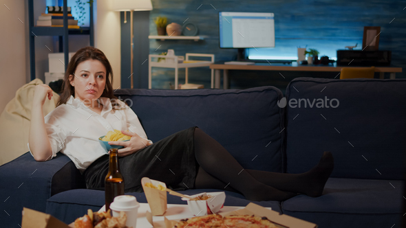 Caucasian adult relaxing on couch with chips as snack