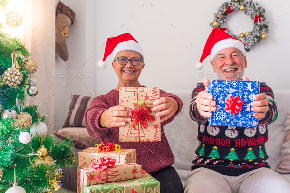 Old people having fun and showing at the camera their gift or present at the camera