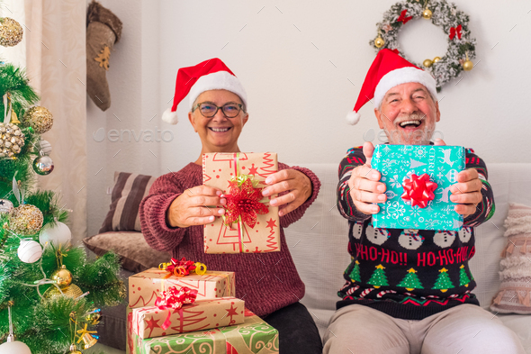 Old people having fun and showing at the camera their gift or present at the camera